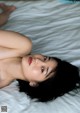 A woman laying on top of a white bed.