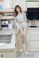 A woman sitting on top of a kitchen counter next to a sink.