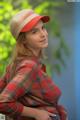 A woman wearing a red plaid shirt and a red hat.