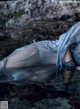 A woman in a blue dress laying in the water.