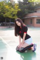 A woman sitting on a basketball court with a basketball.