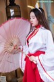 A woman in a red and white dress holding an umbrella.