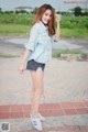 A woman in a denim shirt and shorts posing for a picture.