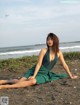 A woman in a green dress sitting on the beach.