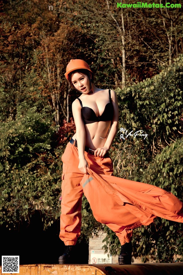 A woman in a black bra top and orange pants posing for a picture.