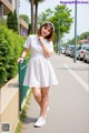 A woman in a white dress is walking down the street.