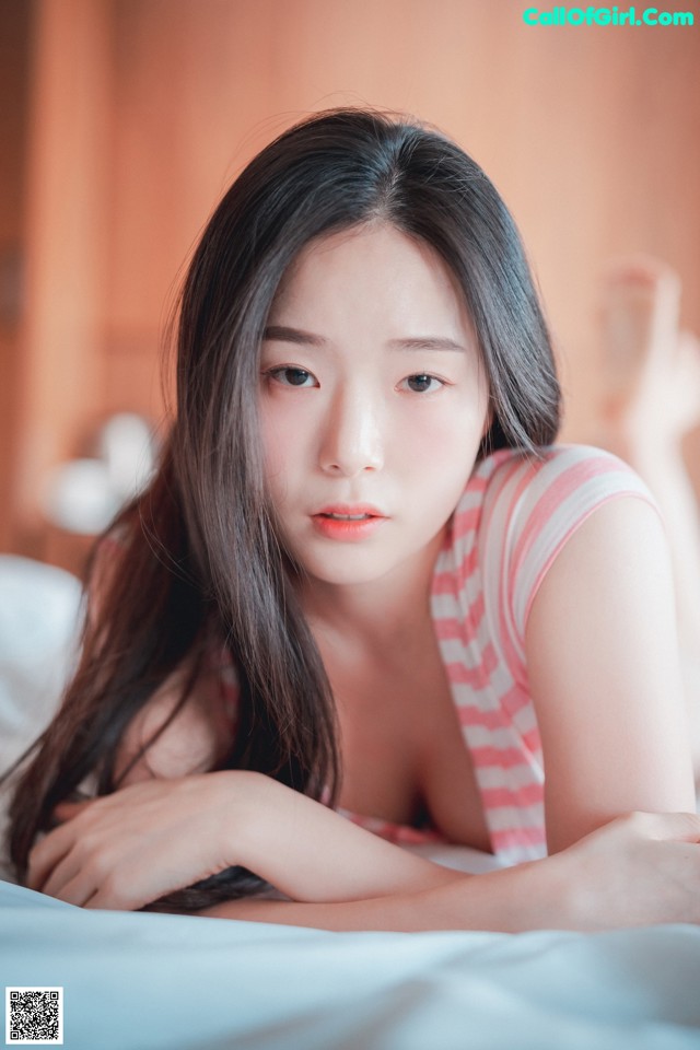 A woman laying on top of a bed next to a pillow.