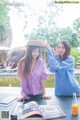 A couple of women sitting at a table next to a pool.