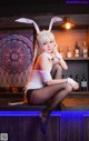 A woman in a bunny costume sitting on a bar.