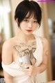 A woman with a tattoo on her chest holding a cup of coffee.