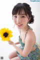 A woman sitting on a couch holding a sunflower.