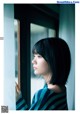 A woman looking out of a window with her hand on the window sill.